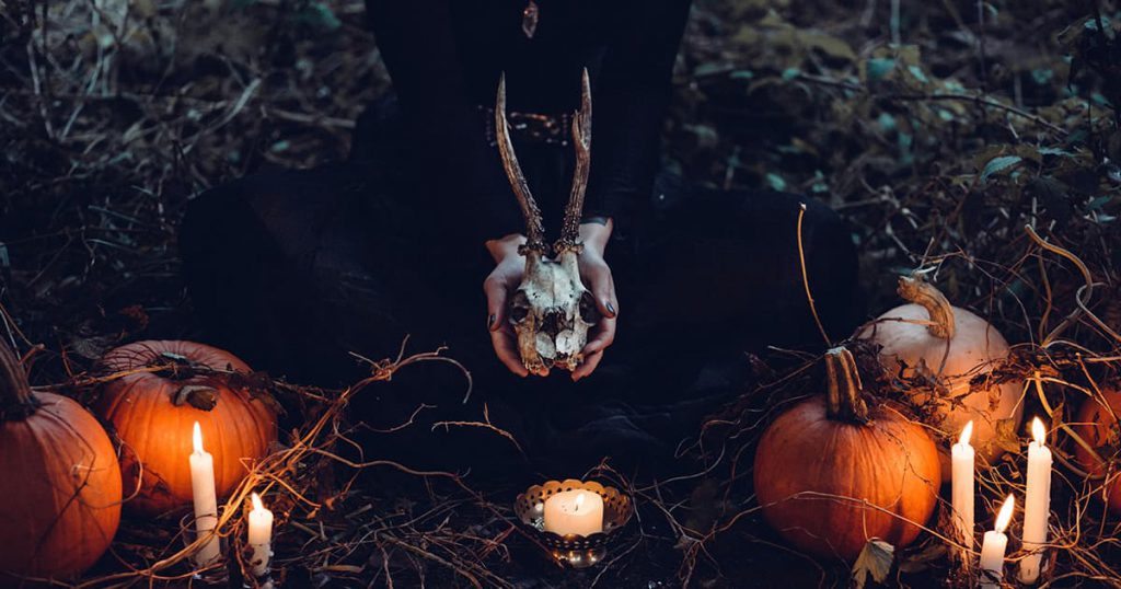 Witchcraft - Hands holding animal skull - pumpkins - candles